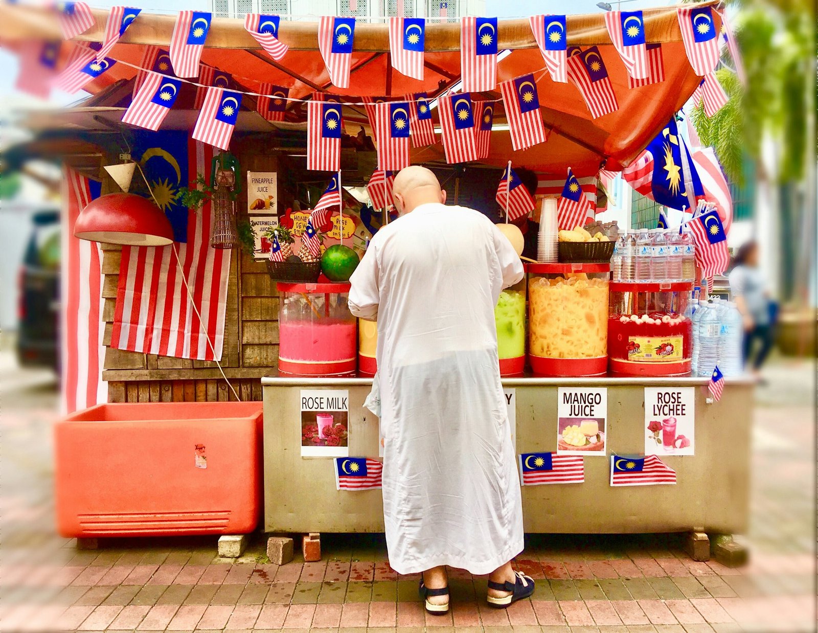 People from behind, male customer purchasing drink/s from street stall